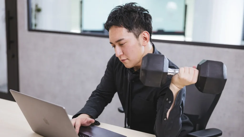 ダンベル片手に仕事をする男性