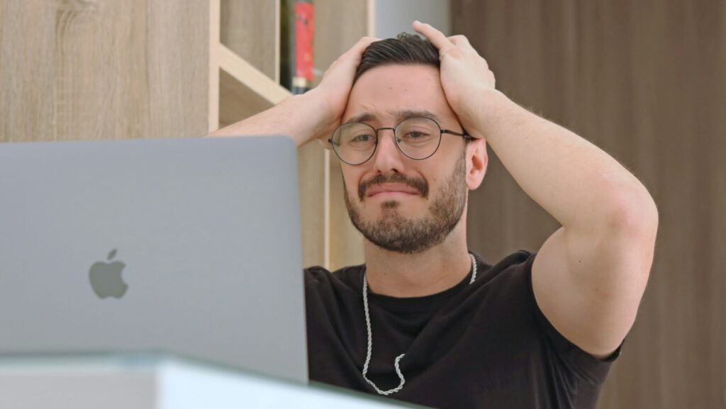 パソコンがフリーズして頭を抱える男性