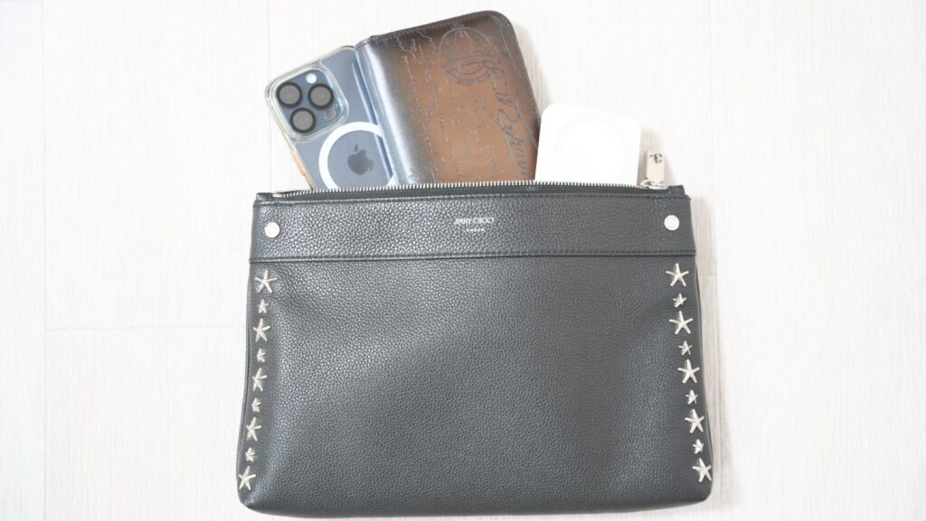 ジミーチュウのクラッチバッグから飛び出したiPhoneと財布とモバイルバッテリー