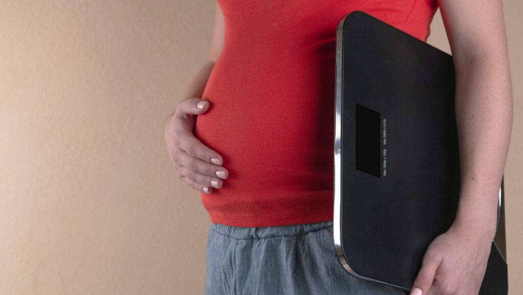 体重計を片手に持つ太った男性